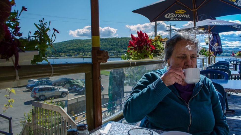 middle-aged woman sipping coffee on the terrace of a café